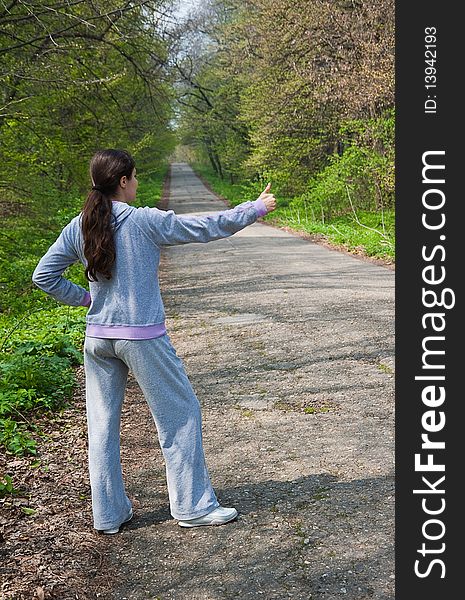 Young woman, standing at the side of the mountain road, hitch-hiking. Young woman, standing at the side of the mountain road, hitch-hiking