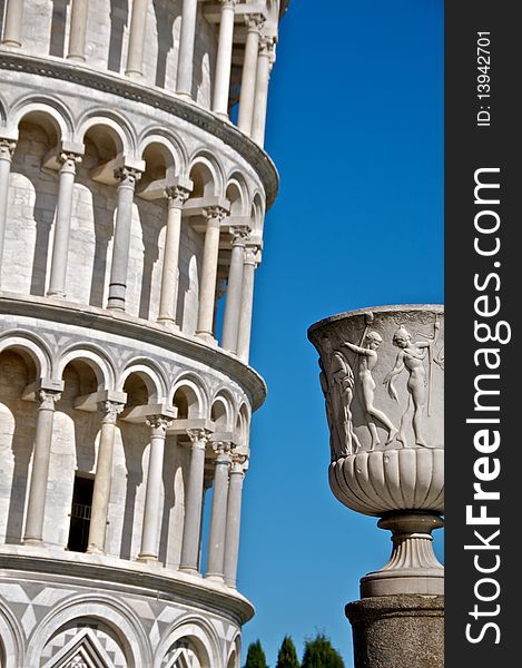 An urn, with a section of the leaning tower of Pisa in the background. An urn, with a section of the leaning tower of Pisa in the background.