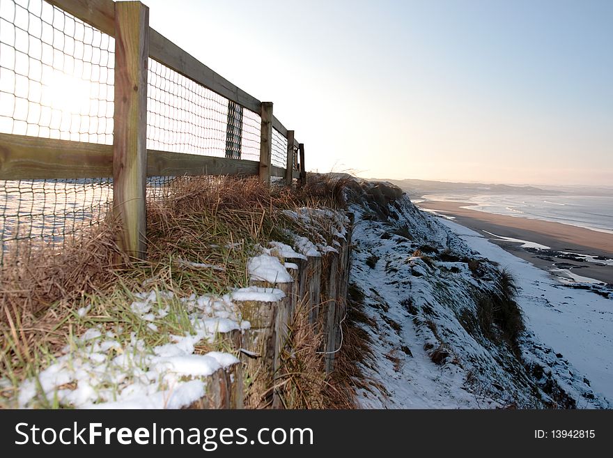 Cliff edge fence over a beach on a cold winters day. Cliff edge fence over a beach on a cold winters day
