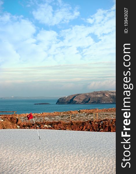 Snow covering on a golf course in ireland in winter with sea and cliffs in background. Snow covering on a golf course in ireland in winter with sea and cliffs in background