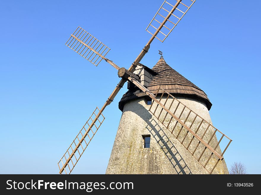 A windmill is a machine which converts the energy of wind to rotational motion by means of adjustable vanes called sails. The main use is for a grinding mill powered by the wind, reducing a solid or coarse substance into pulp or minute grains. A windmill is a machine which converts the energy of wind to rotational motion by means of adjustable vanes called sails. The main use is for a grinding mill powered by the wind, reducing a solid or coarse substance into pulp or minute grains.