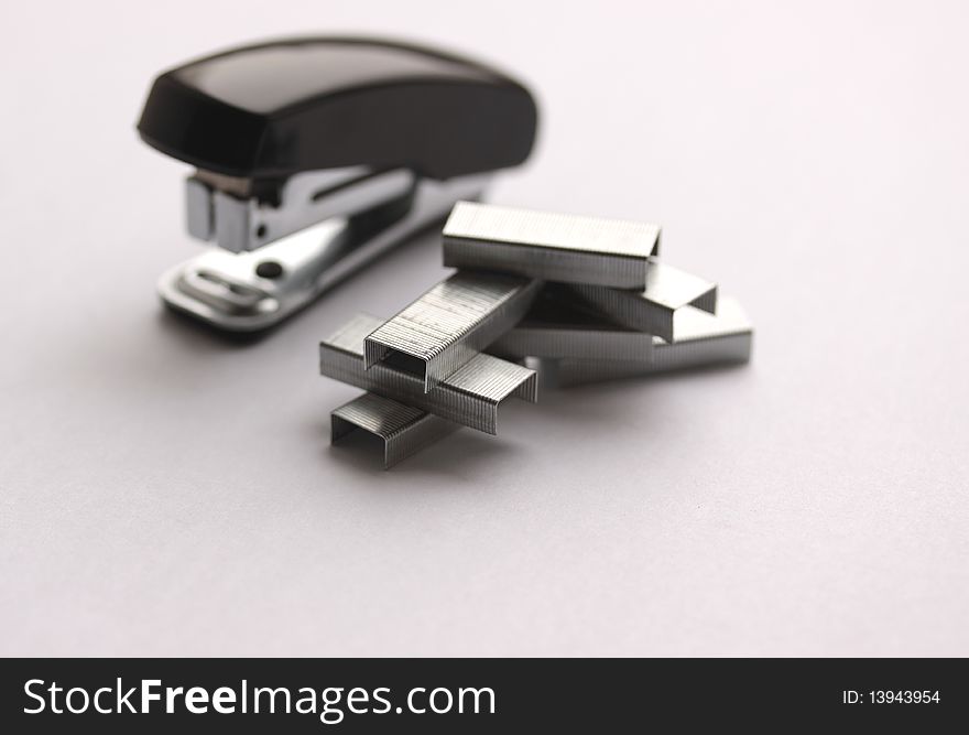 Clips and stapler on light grey background (small depth of sharpness)