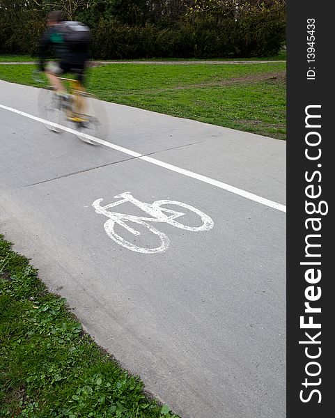 Biker on a biking path in a park (motion blur is used to convey movement)