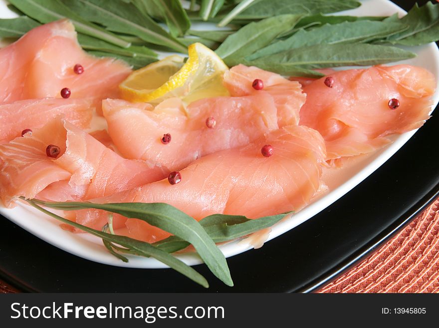 A dish of smoked salmon with red pepper and rocket. A dish of smoked salmon with red pepper and rocket