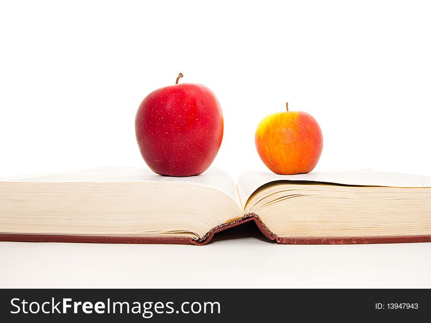 The thick book and apples on a white background