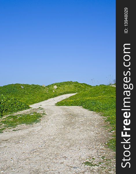 Photo of a dirt path through a green meadow over a blue clear sky, photo taken in Um-Qais - Jordan. Photo of a dirt path through a green meadow over a blue clear sky, photo taken in Um-Qais - Jordan