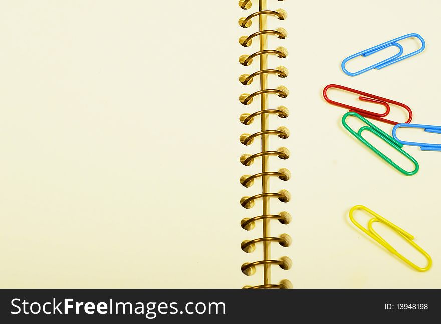 Notebook - empty page and bright paper clips. Notebook - empty page and bright paper clips