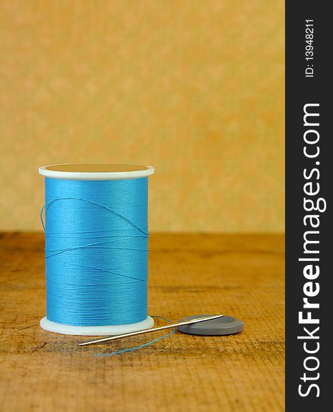 Spool of Blue Thread with a Needle and Button