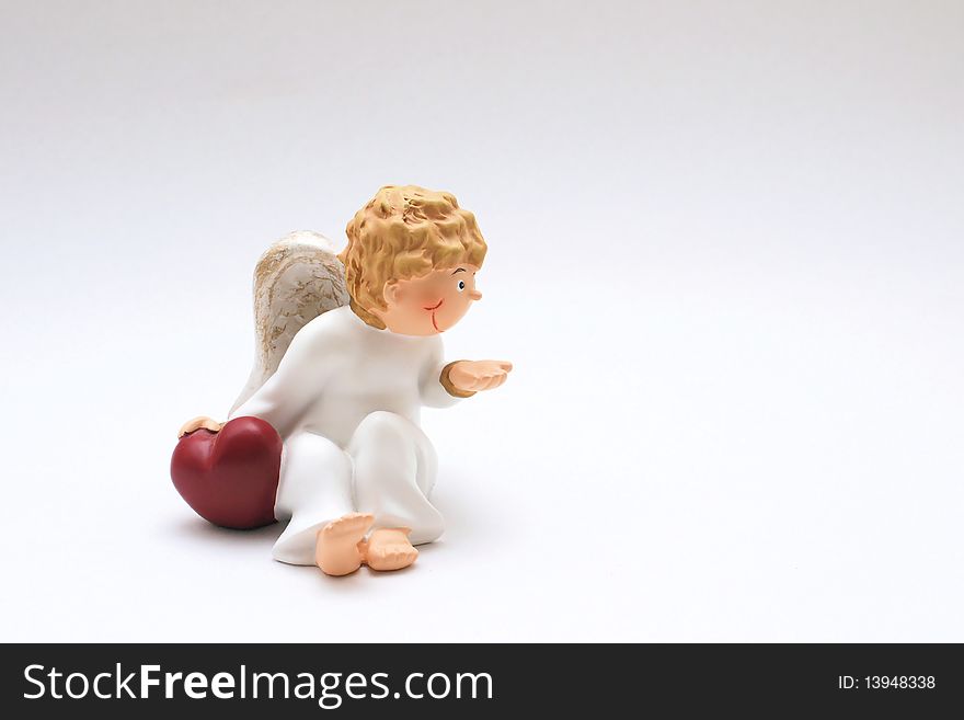 Figure of a curly-headed, childlike angel holding one hand on a red heart. Figure of a curly-headed, childlike angel holding one hand on a red heart