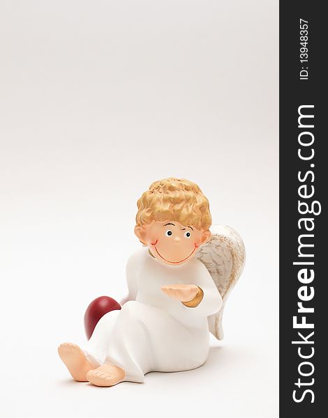 Figure of a curly-headed, childlike angel holding one hand on a red heart. Figure of a curly-headed, childlike angel holding one hand on a red heart