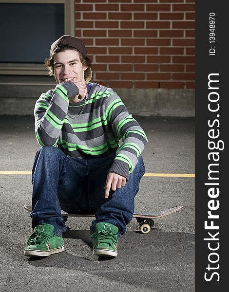 Young Skateboarder Sitting On His Board