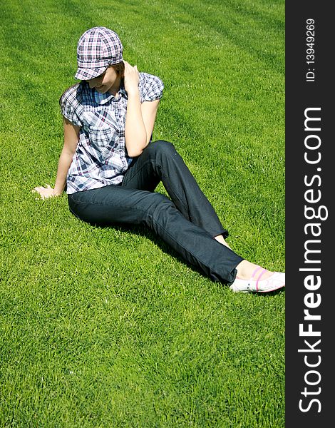 Young caucasian girl sitting on the green grass. Young caucasian girl sitting on the green grass