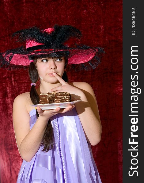 Lovely teen girl in dress and hat with cake