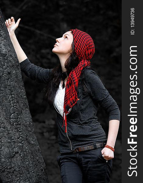 Girl in a red kerchief hugs charred wood. Girl in a red kerchief hugs charred wood