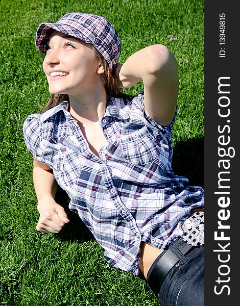 Young caucasian girl sitting on the green grass, spring rest