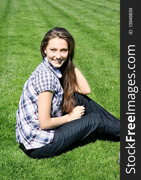 Young caucasian girl sitting on the green grass. Young caucasian girl sitting on the green grass