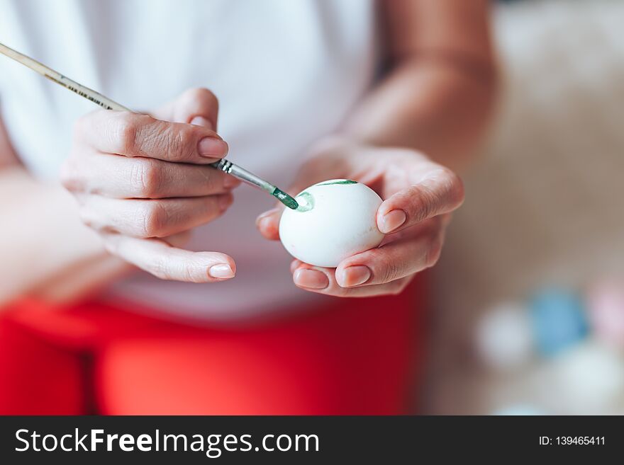 Hands painting modern style easter eggs with red green paint selected focus