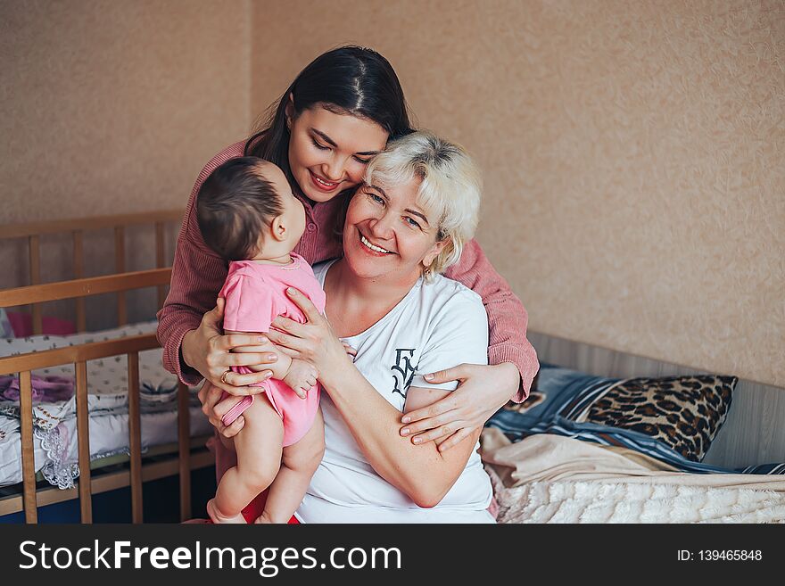 Little cute girl, her attractive young mother and charming grandmother are spending time together at home. Women& x27;s generation. Happy International Women& x27;s Day