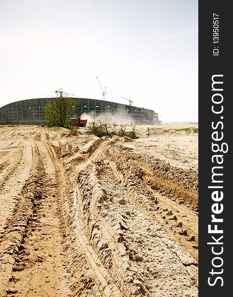 A view of a yellow construction water tanker truck spraying water for dust control at construction site. A view of a yellow construction water tanker truck spraying water for dust control at construction site.