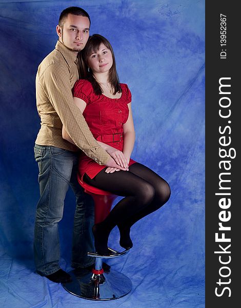 Young woman sitting on a chair with her boyfriend standing near. Young woman sitting on a chair with her boyfriend standing near