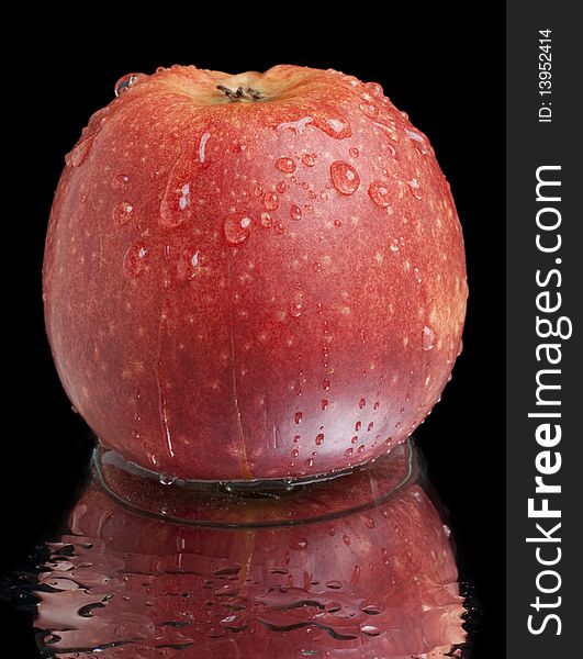 Wet red apple with reflection on black