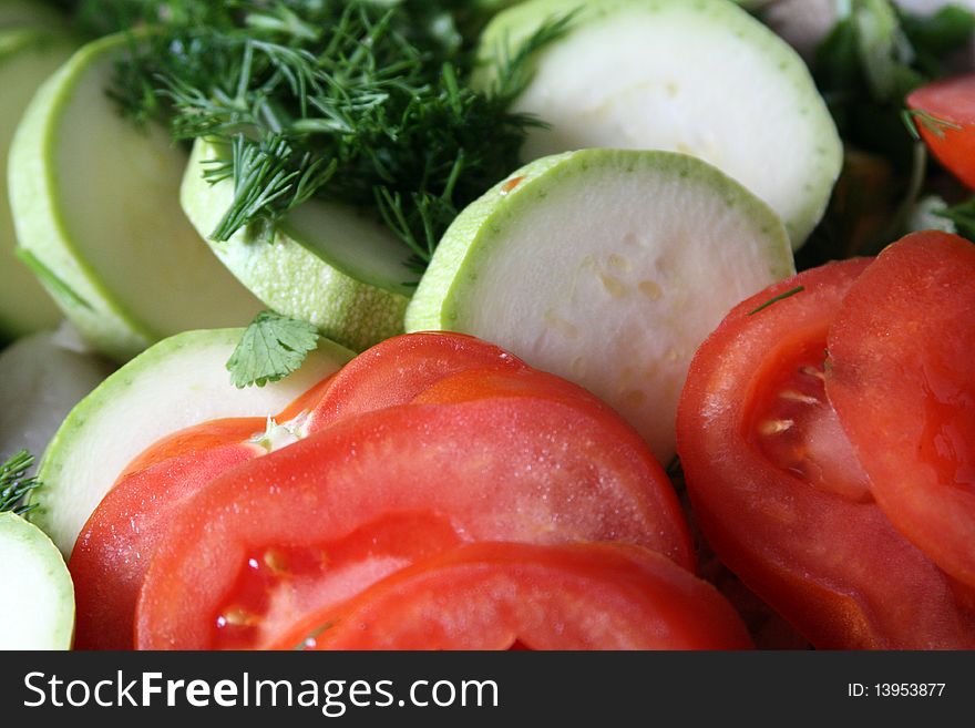 Bright red tomato and zucchini slices sprinkled with chopped dill. Bright red tomato and zucchini slices sprinkled with chopped dill