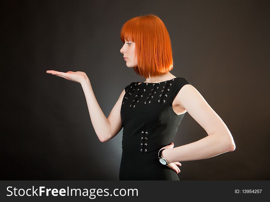 Beautiful red girl in an evening dress against a dark background. Beautiful red girl in an evening dress against a dark background