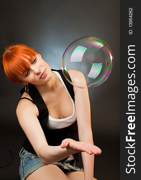 Beautiful red girl catches a hand a soap bubble. Beautiful red girl catches a hand a soap bubble