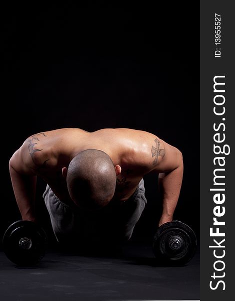 Young bald strong man is working out over black background. Young bald strong man is working out over black background.