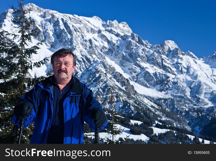 An active  senior man with snowshoes in a winter setting in the alps. An active  senior man with snowshoes in a winter setting in the alps.