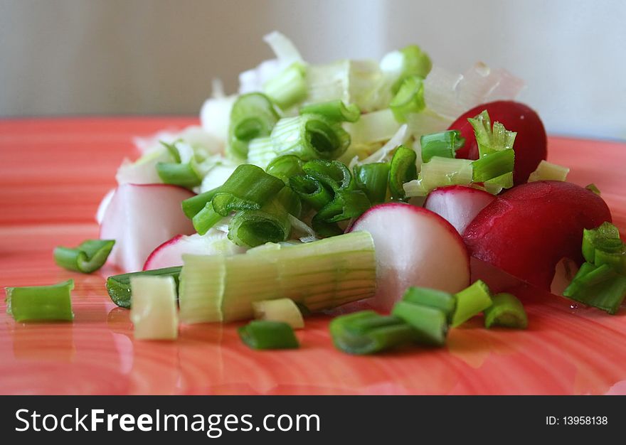 Salad with radishes and onions on an orange plate
