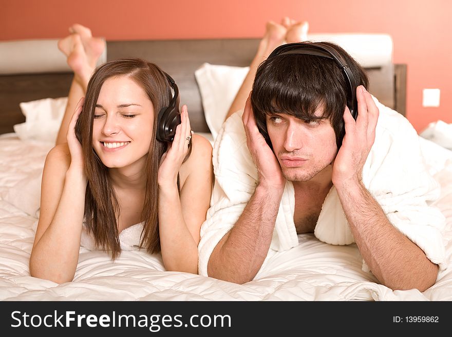 Girl with smile and boy in headphones on bed. Girl with smile and boy in headphones on bed