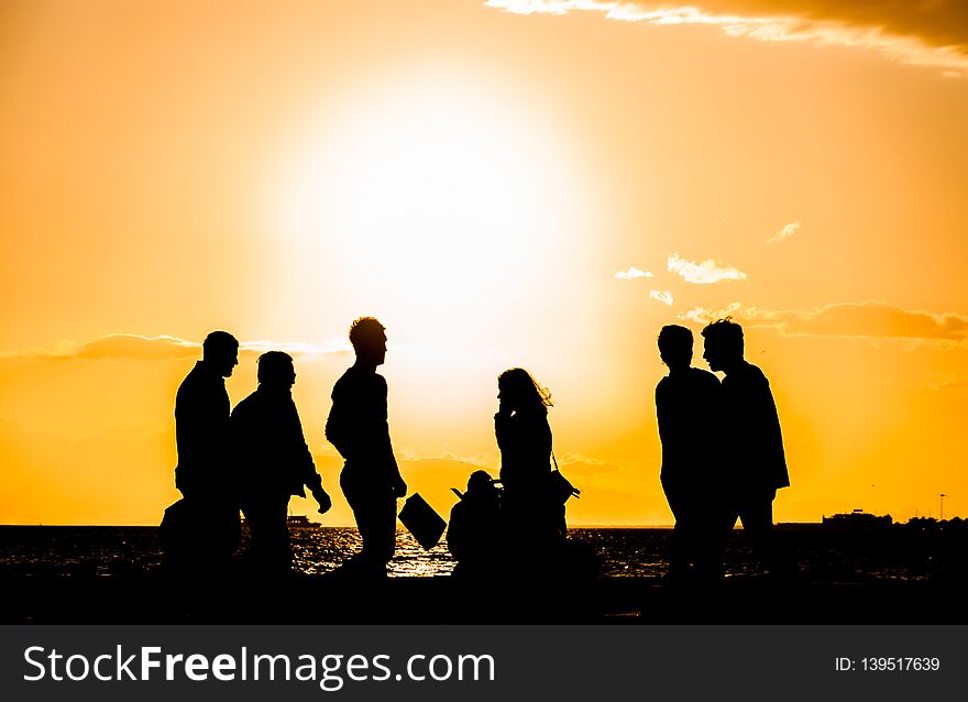 A group of people silhouette walking at the seaside at sunset in Izmir, Turkey