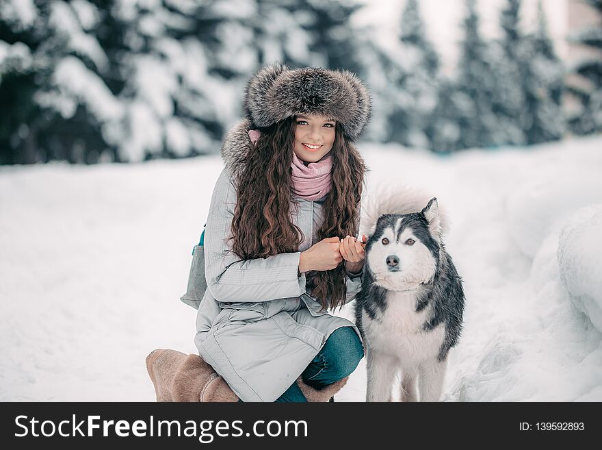 girl in fur hat with black and white husky