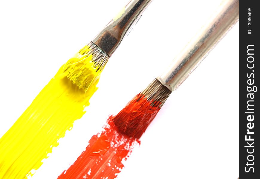 Two paintbrushes drawing a yellow and a red line. Two paintbrushes drawing a yellow and a red line