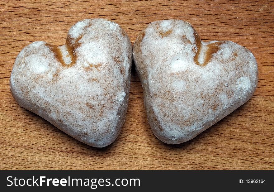 Two sweet ginger breads in the form of hearts on a background of a chopping board