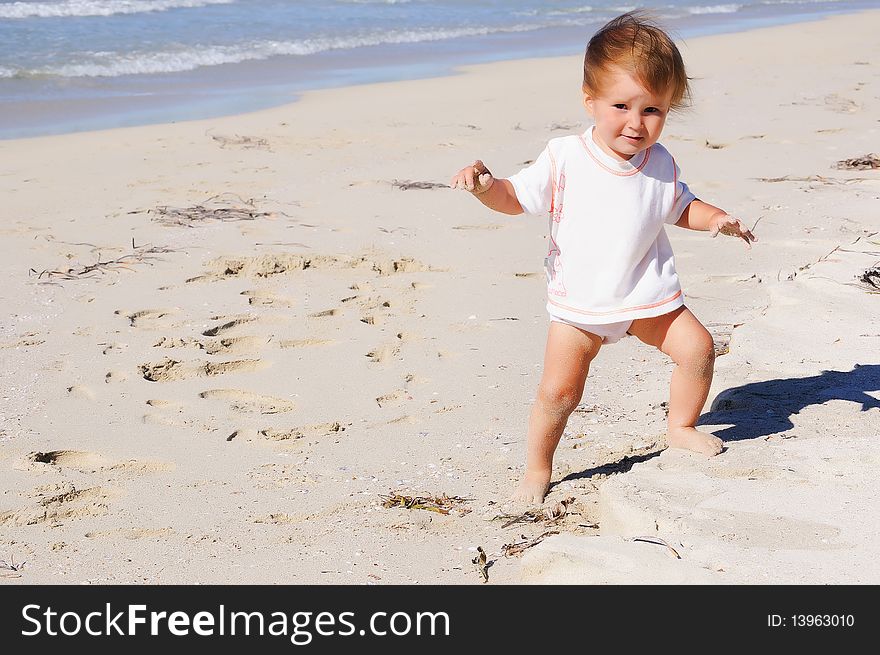 Charming little girl running on the golden beaches near the ocean blue