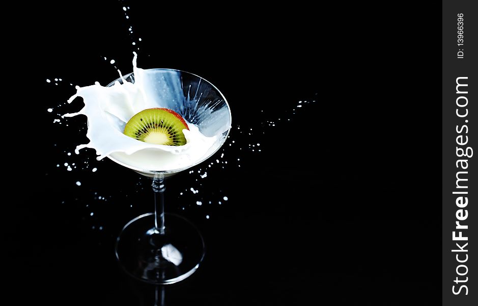 Kiwi Fruit splashing into a martini glass filled with milk. Isolated on black. Kiwi Fruit splashing into a martini glass filled with milk. Isolated on black.