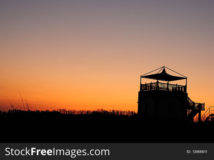 Sunset silhoutte of house with free space above.