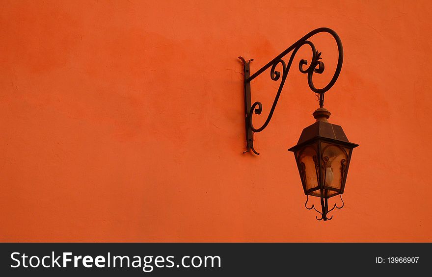 Antique street lamp mounted on the wall of a building.