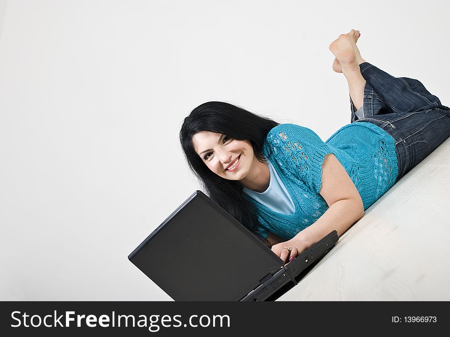 Happy beautiful woman lying down on wooden floor and using a laptop,copy space for text message,see more in People on couch or wooden floor. Happy beautiful woman lying down on wooden floor and using a laptop,copy space for text message,see more in People on couch or wooden floor