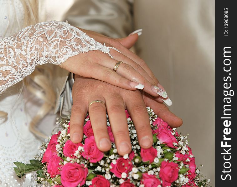 Newly married - hands with gold rings on a beautifull wedding bouquet