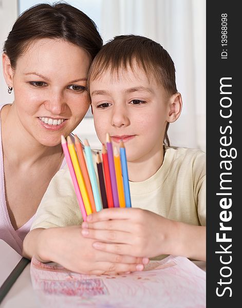 Young mother sits with her son and look at pencils. Young mother sits with her son and look at pencils