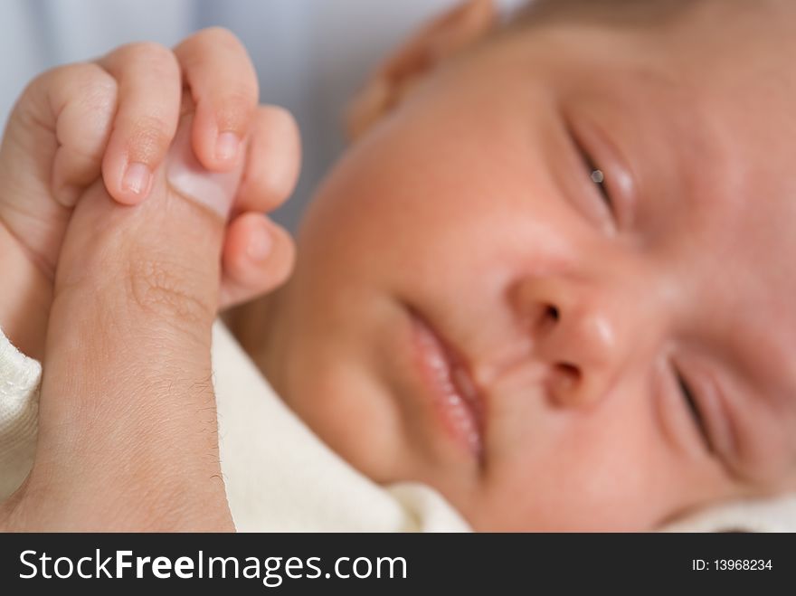 Newborn sleeping peacefully and keeps finger father