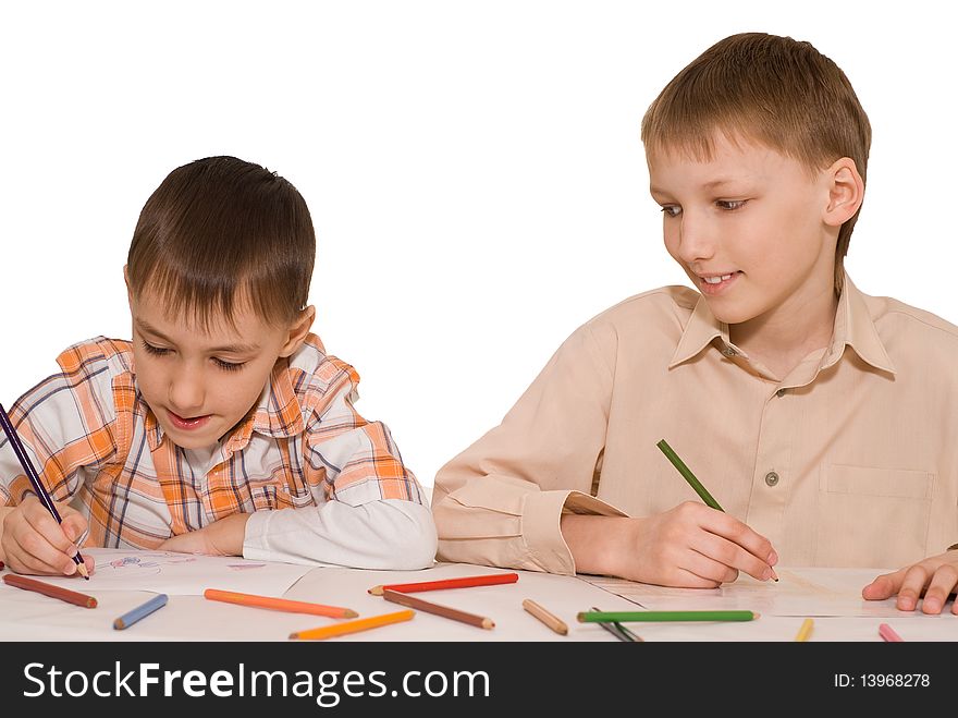 Two brothers sit at the table and draw