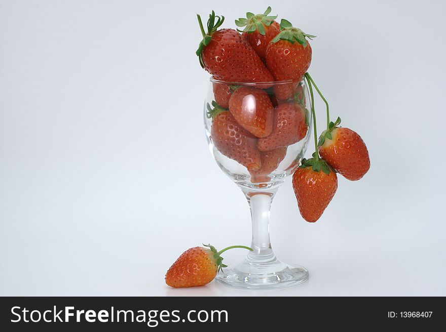 Upright wine glass, filled to the brim with red strawberries on a white background. Upright wine glass, filled to the brim with red strawberries on a white background.