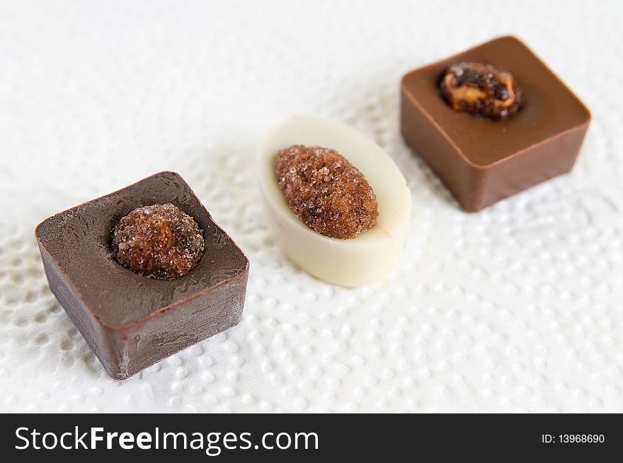 Chocolate candies with nuts on white surface. Chocolate candies with nuts on white surface