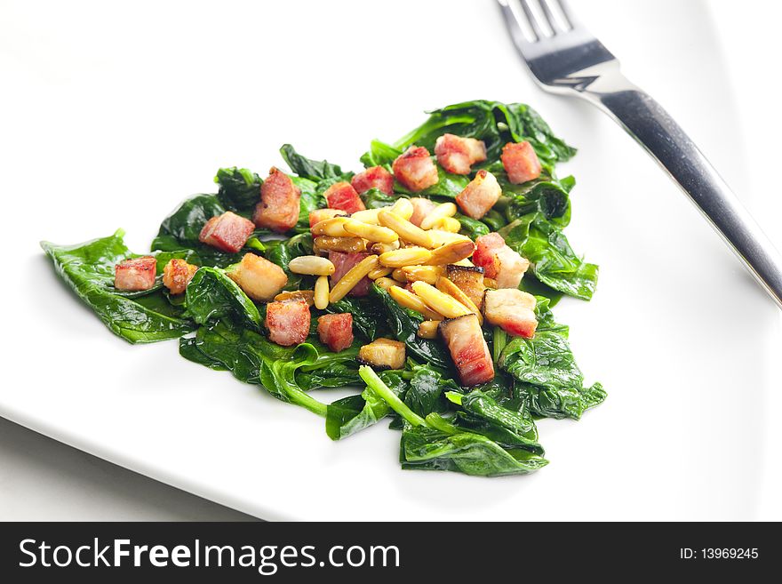 Fried spinach with bacon and pine nuts