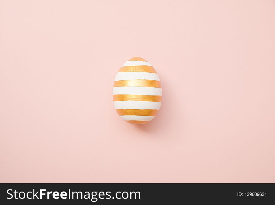 Easter golden with striped patternd egg on pastel pink background. Minimal easter concept. Happy Easter card with copy space for