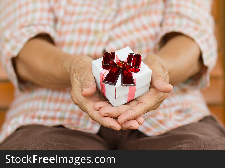 Eldery person hold a gift box in hand. Concept of Support, help, nursing home or help for elderly